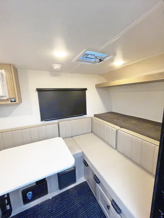 RV rental's versatile interior: a U-shaped dinette with light cushions, white table, and darker convertible bunk bed.. Forest River Flagstaff E-Pro 2026