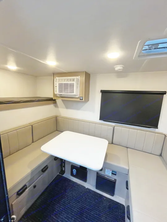 An RV rental interior with a U-shaped dining area, bunk bed, AC, and window blinds.. Forest River Flagstaff E-Pro 2026