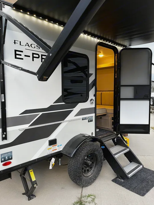 Flagstaff E-Pro RV rental: a compact travel trailer with an illuminated awning and inviting open doorway for adventure.. Forest River Flagstaff E-Pro 2026