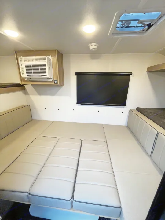 Interior of an rv rental, featuring a convertible bed/seating area, wall AC unit, retractable screen, ceiling lights, and a vent.. Forest River Flagstaff E-Pro 2026