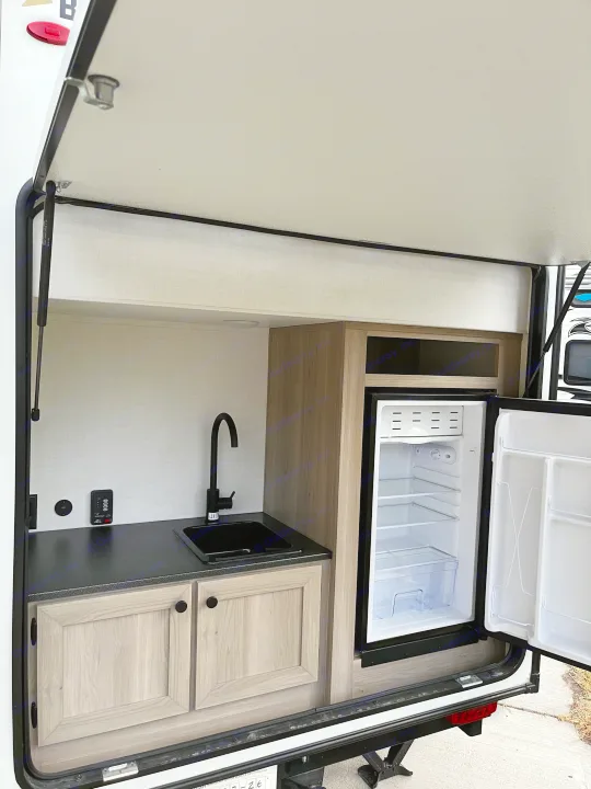 Explore this RV rental's outdoor kitchen! Features a sink, mini-fridge, and cabinets for convenient camping meals.. Forest River Flagstaff E-Pro 2026