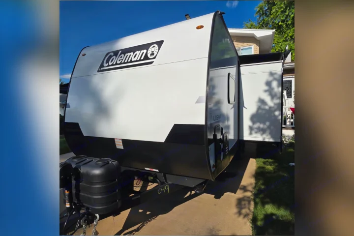 Get ready for outdoor adventure! A white & black Coleman travel trailer RV rental, parked in a sunny driveway.. Keystone Coleman 22BX 2027