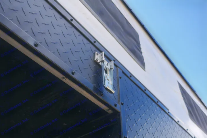 RV rental's exterior featuring a rugged diamond-plate panel, metal latch, and canvas wall with vents against a blue sky.. Four Wheel Campers Shell Models 2020