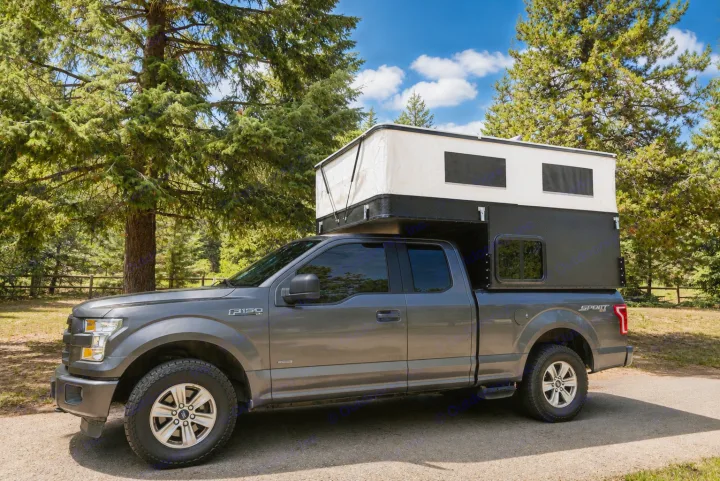Grey Ford F-150 pickup with pop-up camper, ideal RV rental for a forest camping adventure.. Four Wheel Campers Shell Models 2020