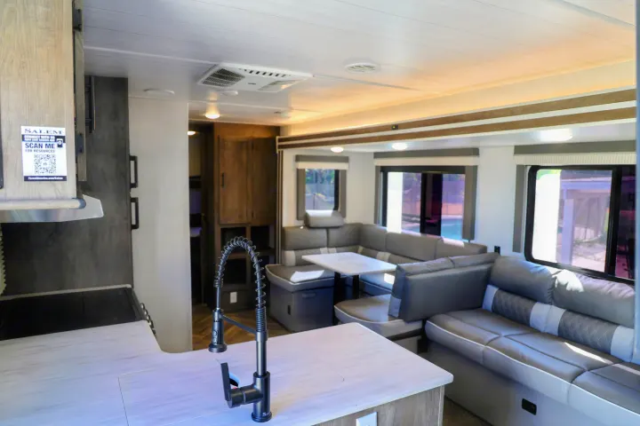 Spacious RV rental interior: modern kitchen with sleek faucet, U-shaped dinette, and bright living area with windows.. Forest River Salem Cruise Lite 2022