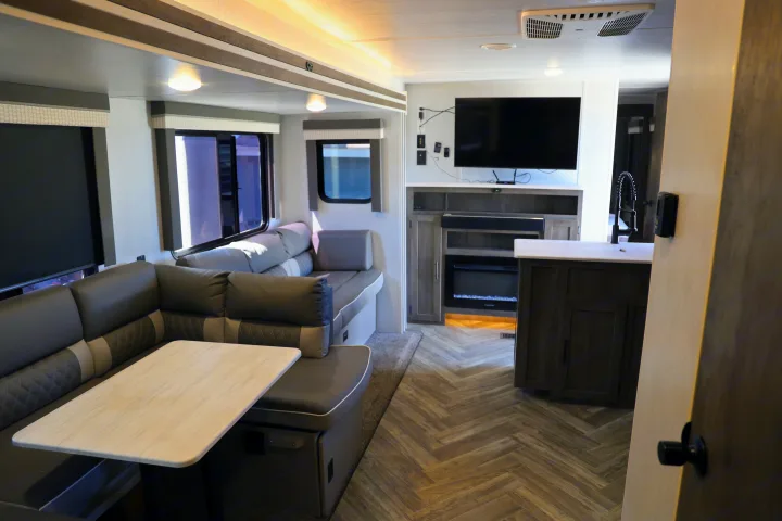 Modern RV rental living area with comfy dinette, TV, fireplace, and a partial view of the kitchen.. Forest River Salem Cruise Lite 2022