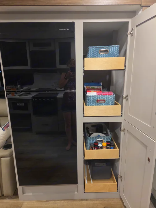 RV rental kitchen featuring a sleek Furrion fridge and a smartly organized pantry with pull-out shelves for snacks, spices, and a toaster.. Alliance RV Delta 2026