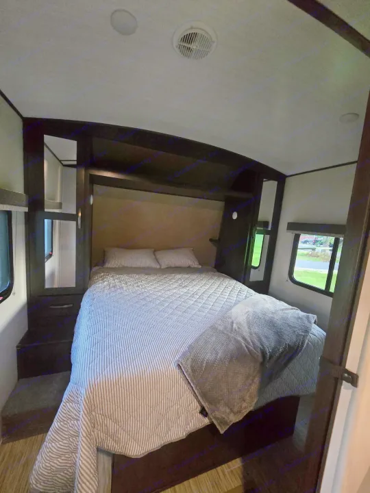 Cozy RV rental bedroom with striped bedding, built-in storage, windows, and ceiling lights/vent, perfect for travel.. Forest River Surveyor Legend 2020