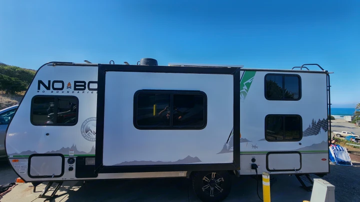 No Boundaries RV rental at a beach campsite. This white travel trailer has a pop-out, with mountain graphics & ocean views.. No Boundaries 19 2022