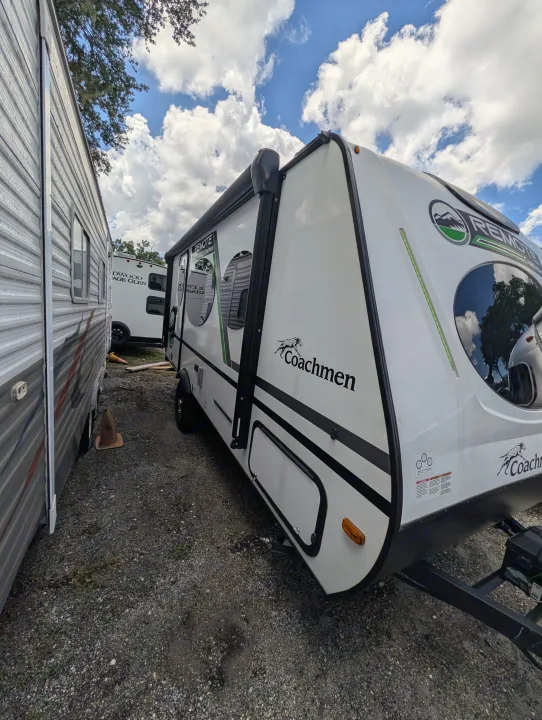 A white Coachmen Remote travel trailer and other RVs parked on a gravel lot, ready for your rv rental. Cloudy sky above.. Coachmen Other 2024