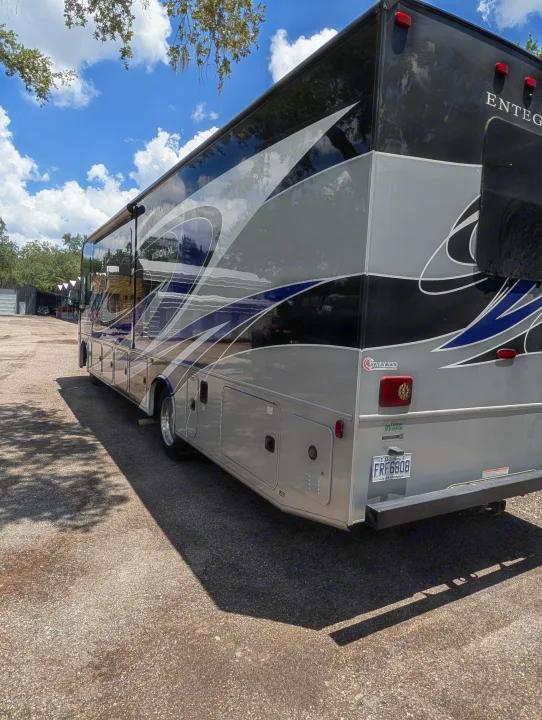 A large Entegra Vision XL RV rental, showcasing its black, silver, and blue design, parked outdoors on a sunny day.. Entegra Coach Vision XL 2022