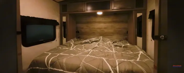 Cozy RV rental bedroom with a large bed, overhead storage, and a window. Perfect for your travel trailer adventures.. Crossroads RV Sunset Trail Super Lite 2022