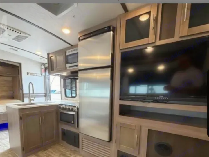 Modern rv rental interior: full kitchen (fridge, stove, microwave, sink) & entertainment area with large TV for comfort.. Crossroads RV Sunset Trail Super Lite 2022