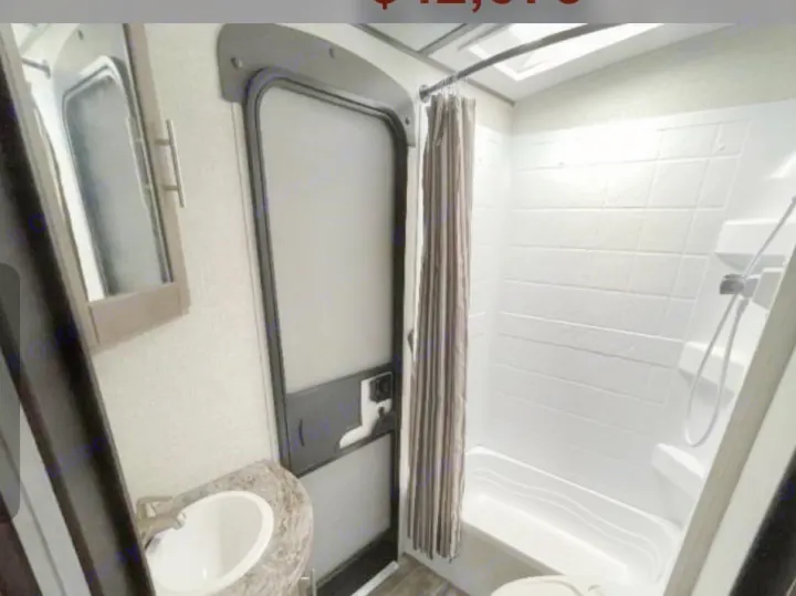 RV rental bathroom with sink, mirrored cabinet, door, shower/tub combo, and partially visible toilet.. Crossroads RV Sunset Trail Super Lite 2022