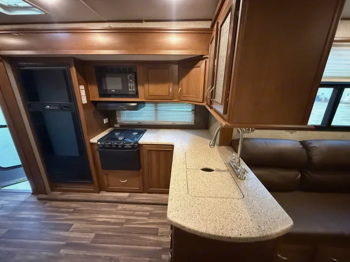 RV rental interior: A well-equipped kitchen with stove, microwave, fridge, and sink, plus a comfy living area.. Highland Ridge Highlander 2016