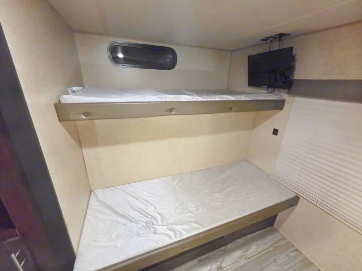 Cozy RV rental bunk beds with a window and TV, offering comfortable sleeping arrangements for travel.. Forest River Cherokee 2017