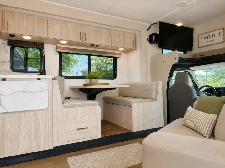 Modern RV rental interior featuring a stylish kitchen, dining booth, and comfortable living area with a TV.. East to West Entrada 2026