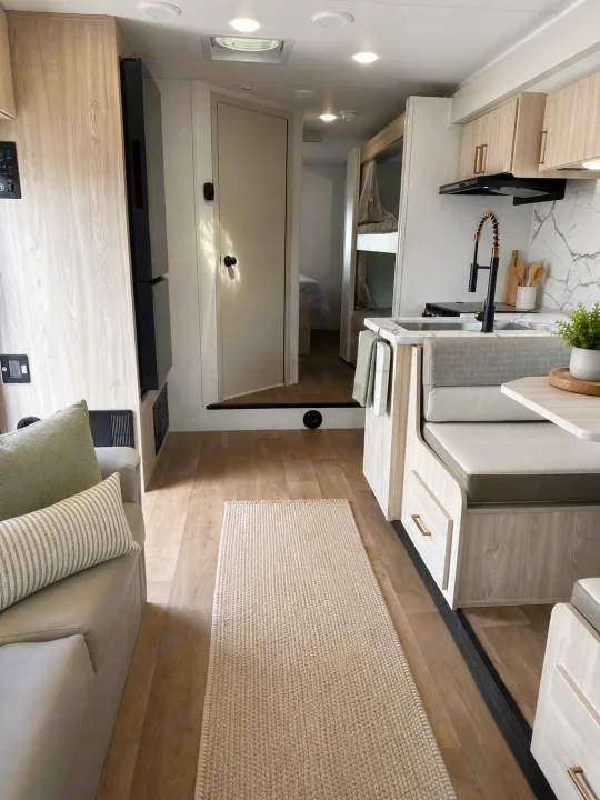 Step into this clean rv rental: bright kitchen with modern faucet, cozy dinette, living space, bunks, and light wood interior.. East to West Entrada 2026