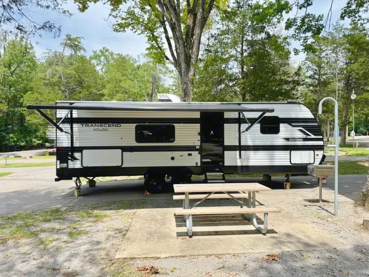 Enjoy this RV rental: a modern travel trailer with awning & picnic table, nestled in a treed campsite.. Grand Design Transcend Xplor 2025