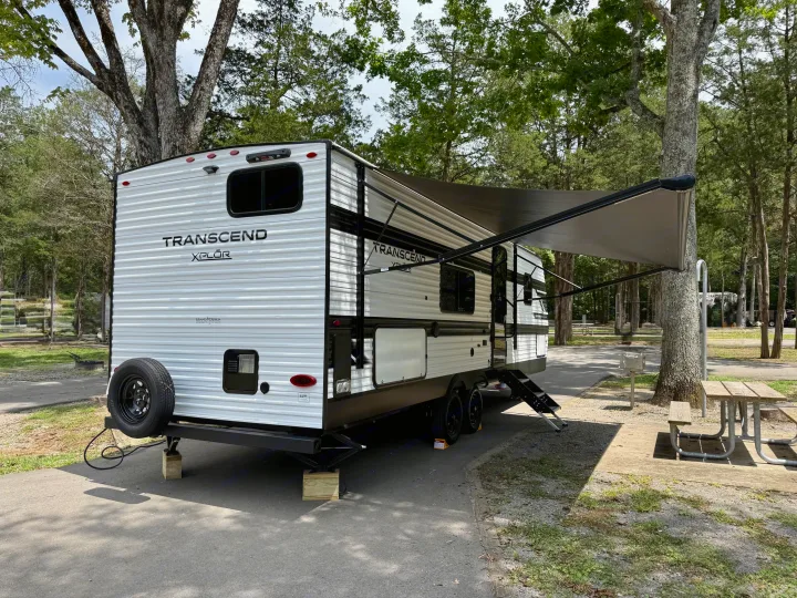 This Grand Design Transcend Xplor rv rental is perfectly set up at a shady campsite with an awning, picnic table & grill.. Grand Design Transcend Xplor 2025