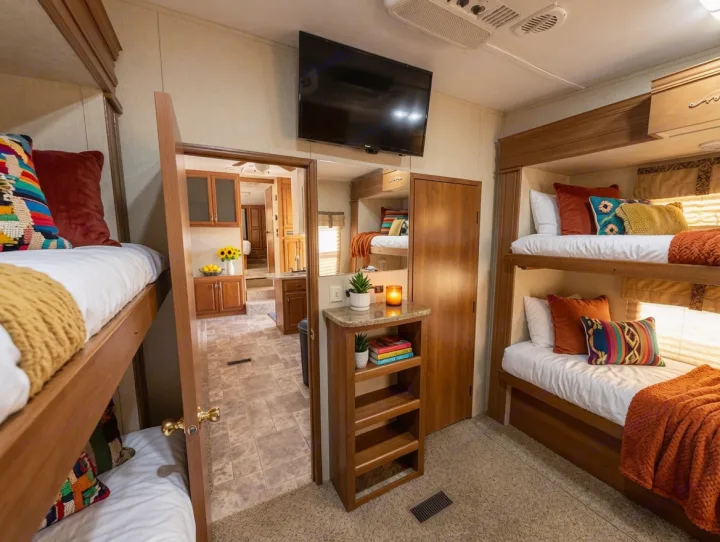Comfortable RV rental interior featuring cozy bunk beds with colorful pillows and a kitchenette visible through the doorway.. Keystone RV Montana High Country 2010