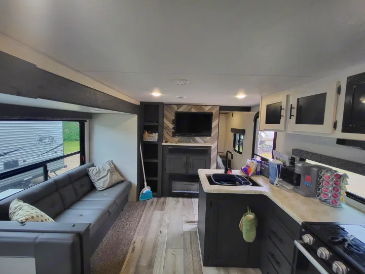 Spacious RV rental interior featuring a modern living area with gray couch, full kitchen, and a fireplace.. KZ Sportsmen SE 332bkhse 2022