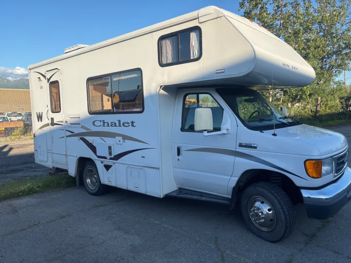 White Winnebago Chalet Class C rv rental parked outdoors, mountains in background.. Winnebago Chalet 2007