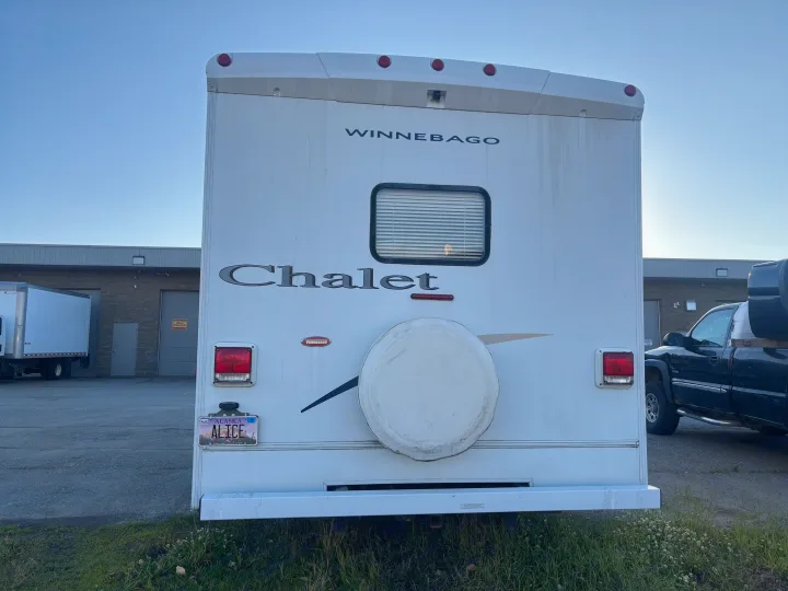 Rear view of a dirty white Winnebago Chalet RV with an 'ALICE' Alaska license plate, ready for your next rv rental journey.. Winnebago Chalet 2007