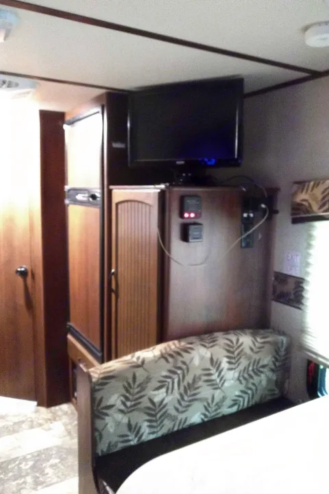 Compact RV rental interior: a comfortable dinette, fridge, and mounted TV create a practical living space for travelers.. Other Other 2015