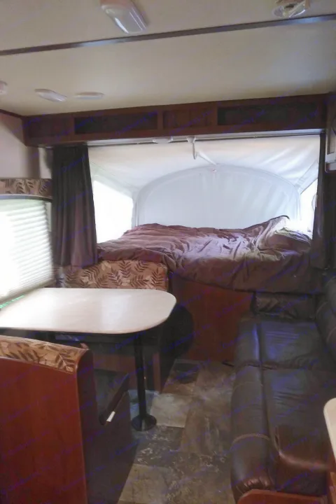 Inside an RV rental, featuring a cozy dinette, expanded pop-out bed area, and comfortable sofa seating.. Other Other 2015