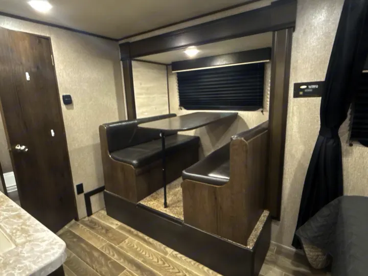 This RV rental offers a compact dinette with upholstered seating, a table, and dark blinds, perfect for dining and relaxing.. Jayco Jay Flight SLX 2021