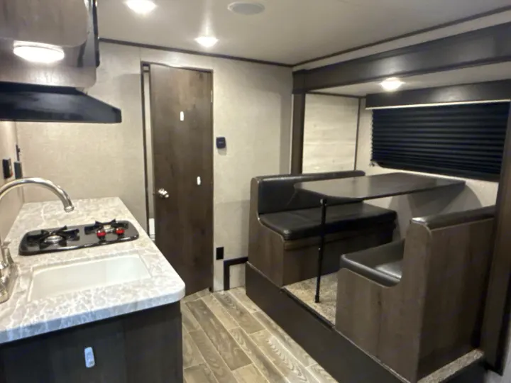 RV rental interior: A modern kitchen with sink/stove, and a comfortable dinette for dining in your travel trailer.. Jayco Jay Flight SLX 2021