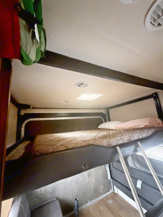 RV rental interior showcasing a practical bunk bed with mattress, pillows, and an access ladder, ideal for extra sleeping.. Forest River Salem Cruise Lite 2018