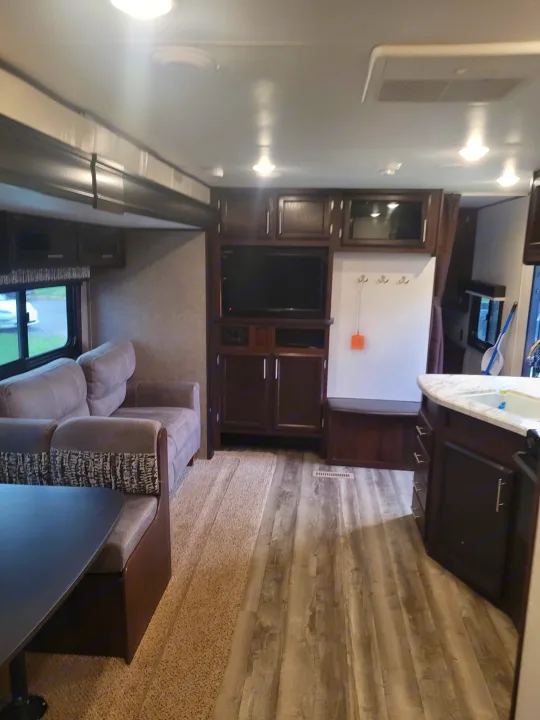 Spacious RV rental interior featuring a dinette, sofa, entertainment center, and kitchen area with light flooring.. Jayco Jay Flight SLX 2019
