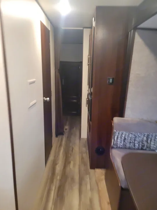RV rental interior: A narrow hallway leading past storage, a dinette, and a door, showing compact modern living.. Jayco Jay Flight SLX 2019