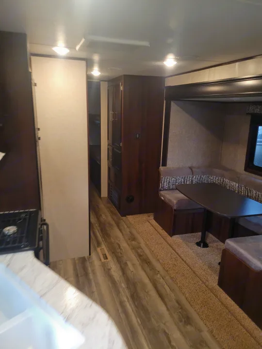 RV rental interior featuring a dining booth with table, kitchen area with sink & stove, and a mix of wood & carpet flooring.. Jayco Jay Flight SLX 2019