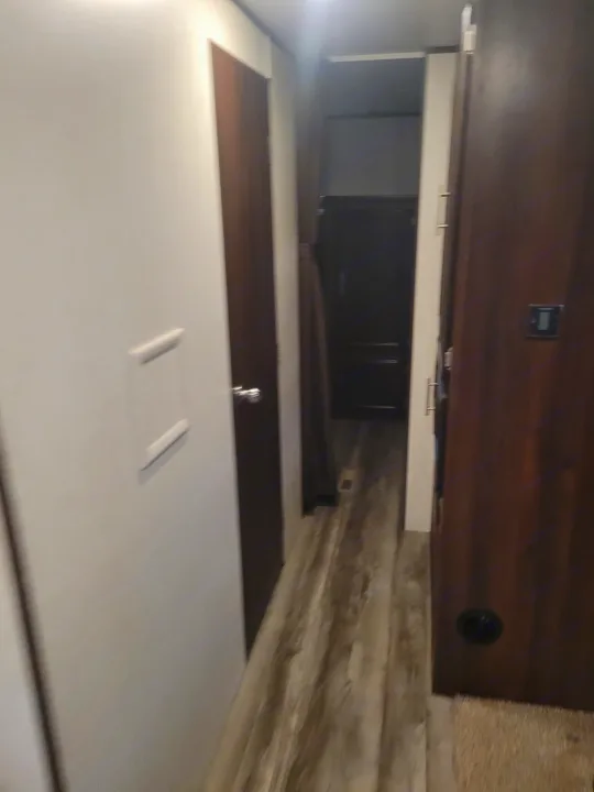 Navigate the compact interior of this rv rental, featuring a narrow hallway with wood-look flooring and multiple doors.. Jayco Jay Flight SLX 2019