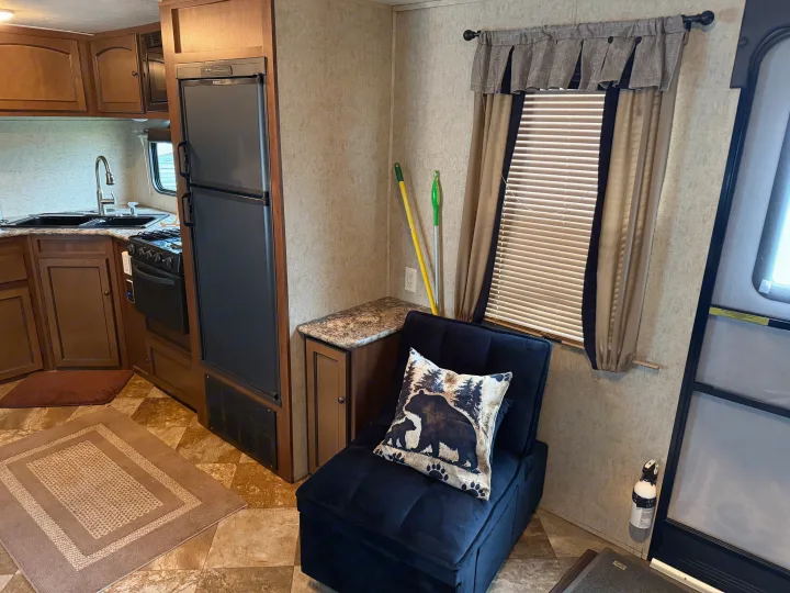 This RV rental interior has a kitchenette with Dometic fridge, stove, sink, and comfy seating by a window.. Layton Layton Trailer 2014