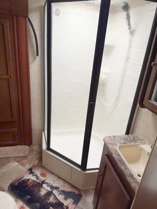 RV rental bathroom with a compact shower, sink, and bear-themed mat. Perfect for your next travel adventure.. Layton Layton Trailer 2014