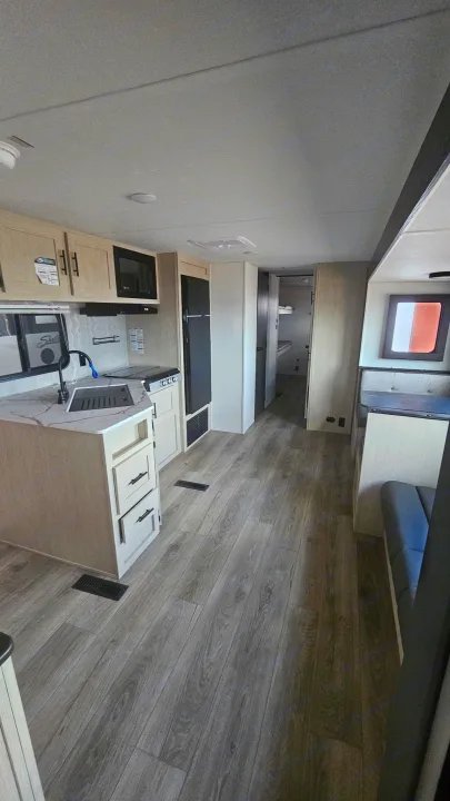 Spacious RV rental interior featuring a modern light wood kitchen, dining booth, and wood-look flooring.. Forest River Shasta I-5 2025