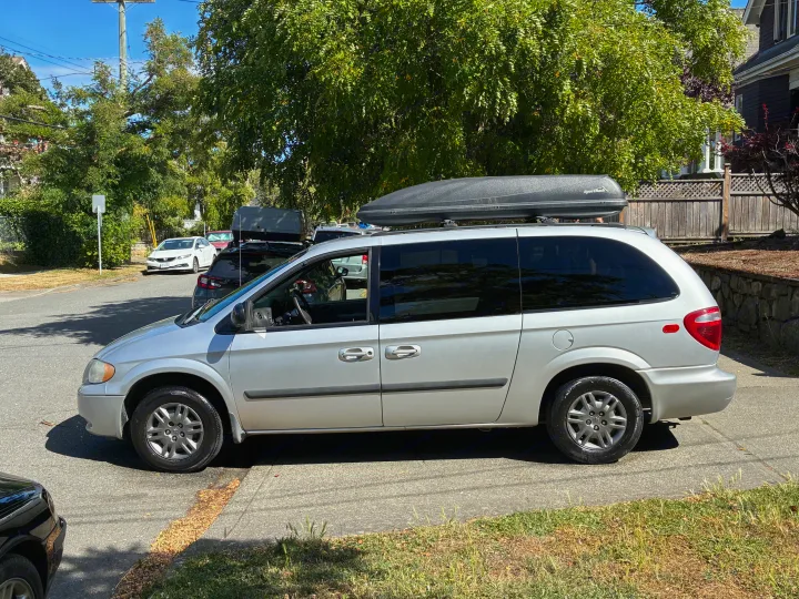 Silver minivan with a SportRack cargo box. Perfect for travel, offering flexibility often sought in RV rental options.. Dodge Grand Caravan 2005