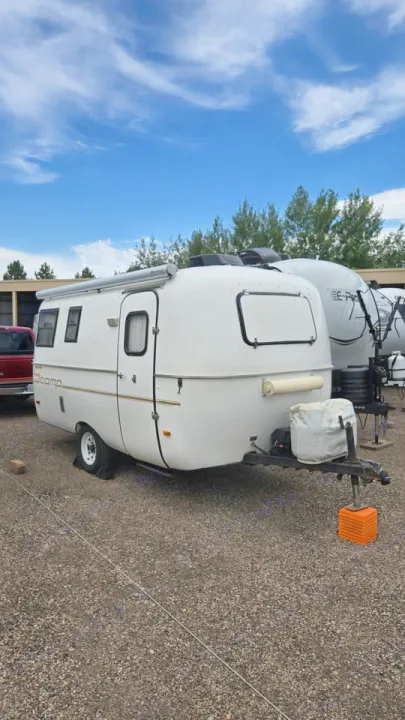 White oCamp travel trailer, perfect for your next RV rental adventure. Parked on gravel under a blue sky.. Scamp Scamp Trailer 2004