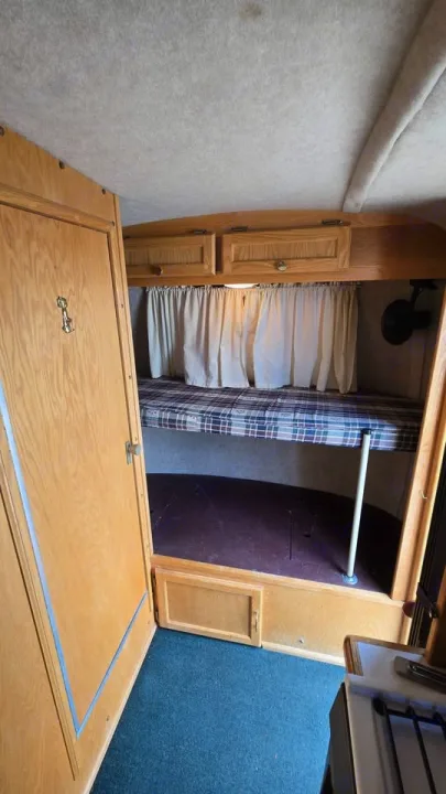 RV rental bunk beds and wooden cabinetry create a functional sleeping area inside this cozy camper interior.. Scamp Scamp Trailer 2004