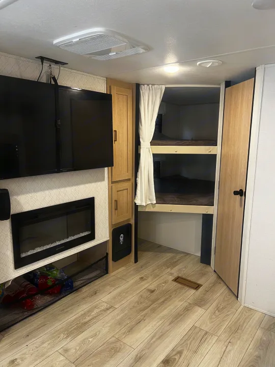 RV rental interior featuring cozy bunk beds, entertainment setup (TV, fireplace), and ample storage.. Avenger Avenger Trailer 2025