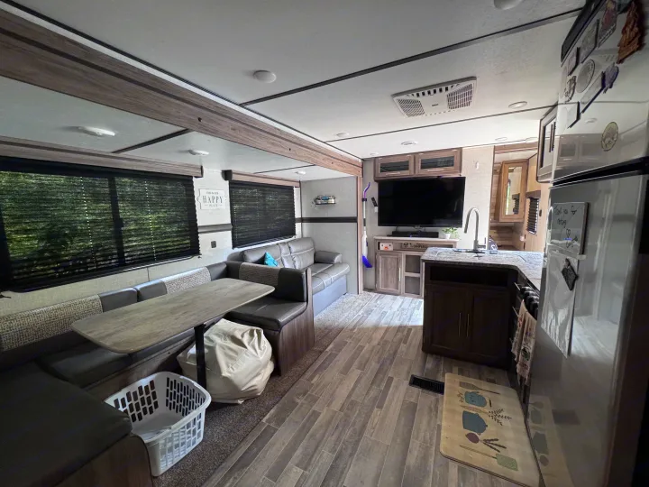 Spacious RV rental interior featuring a comfortable dinette, sofa, kitchen area, and TV—perfect for your next adventure.. Crossroads RV Zinger Lite 2021