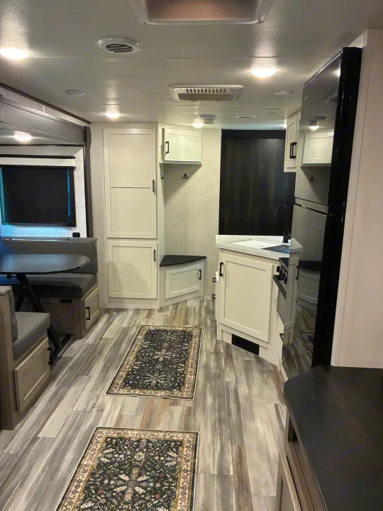 Bright rv rental interior with a modern kitchen, comfortable dining booth, and stylish wood-look flooring.. Jayco Jay Feather 2024