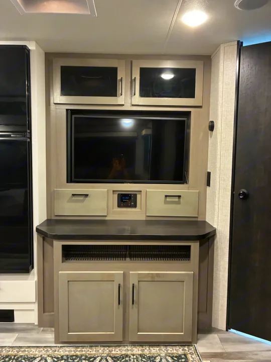 This RV rental's sleek entertainment setup features a TV, stereo, overhead cabinets, drawers, and lower storage baskets.. Jayco Jay Feather 2024