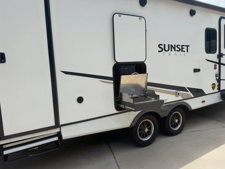 This Sunset Trail RV rental features a convenient outdoor kitchen with a pull-out grill and fridge, perfect for camping.. Crossroads RV Sunset Trail Super Lite 2022