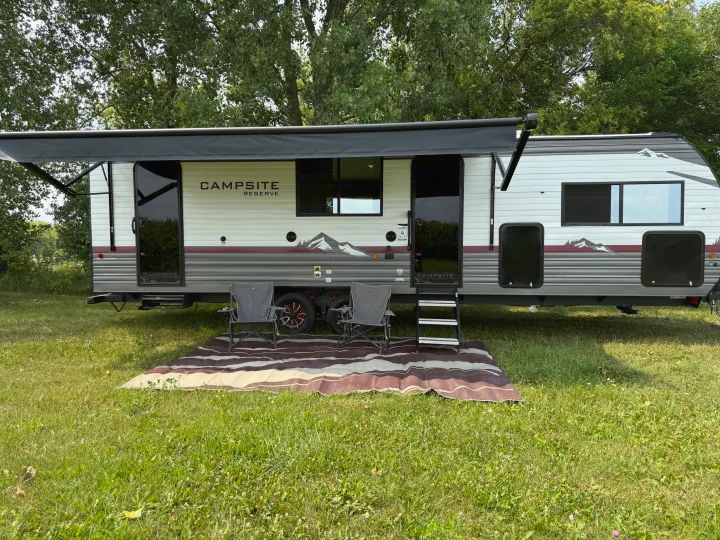 Campsite Reserve **rv rental** setup: travel trailer with extended awning, chairs, and mat on grass. Perfect for a relaxing outdoor stay.. Forest river Campsite Reserve 26cj 2027