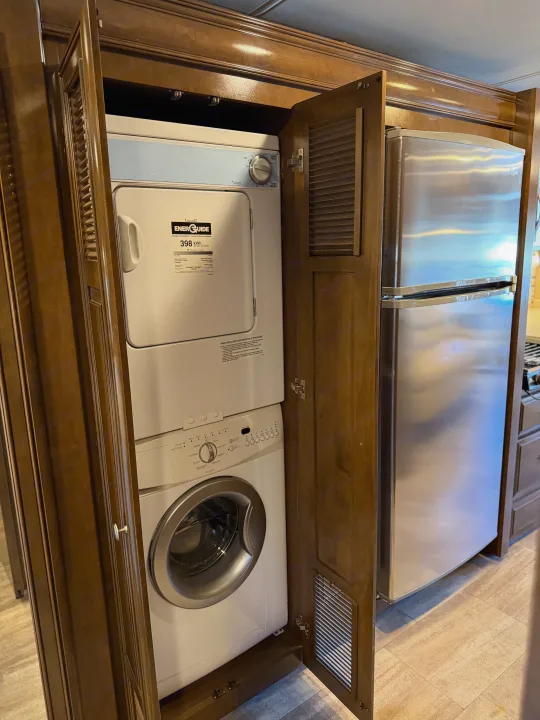 RV rental featuring a compact stacked washer/dryer laundry unit beside a stainless steel refrigerator.. Thor Palazzo 2017